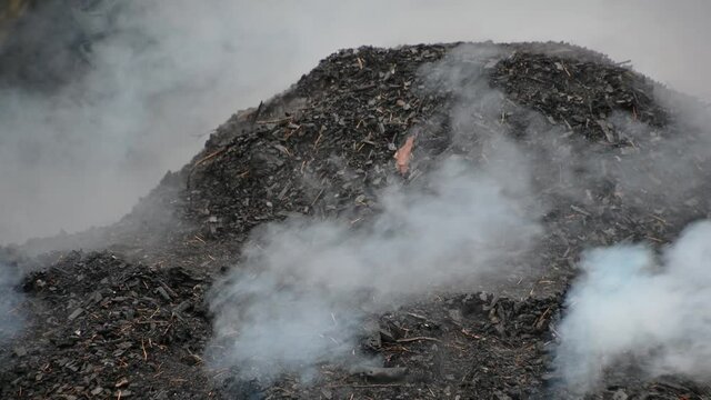 Close up view of a mound of soil smoking while charcoal is being made in rural Slovenia. Pile of steaming coal. Traditional production of charcoal from hardwood. Static shot, real time