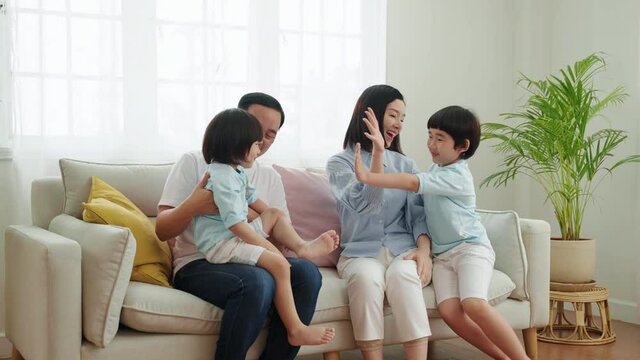 Asian family relationships, children running to hug his parents on the sofa on a family vacation.
