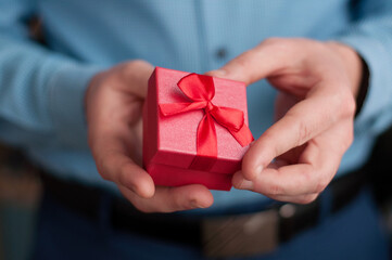 A red box with a bow in the hands of a man in a blue shirt