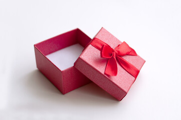 Open red empty box with a red ribbon for a ring with a white soft pad on a white background