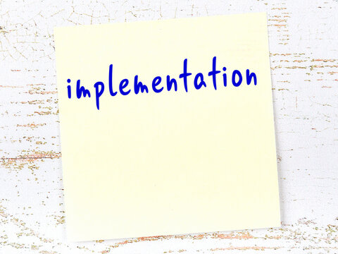 Yellow sheet of paper with word implementation. Reminder concept