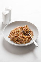 boiled buckwheat porridge with a spoon on a marble table