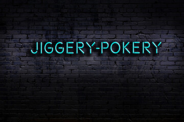 Neon sign. Word jiggery-pokery against brick wall. Night view