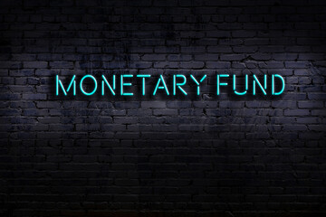 Night view of neon sign on brick wall with inscription monetary fund