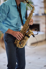 Naklejka premium A male saxophonist in a blue shirt plays the saxophone.