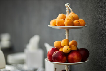 Peaches and apricots on a two-tiered fruit bowl.