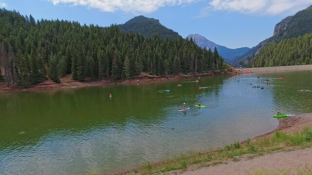 Tibble Fork Reservoir in the Uinta National Forest near Salt Lake City, Utah. Recreationists are using various floatation devices to enjoy the lake. Camera pans left to right.