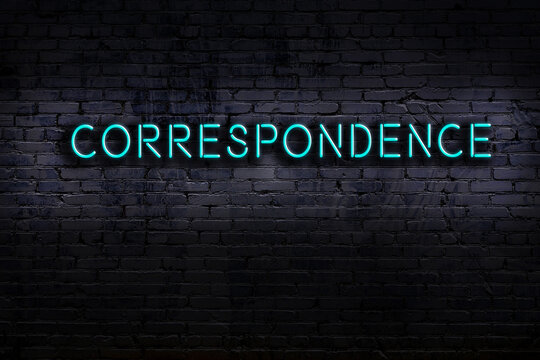 Night view of neon sign on brick wall with inscription correspondence