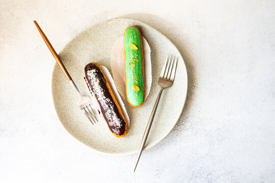 Overhead view of a pistachio and a chocolate eclair on a plate