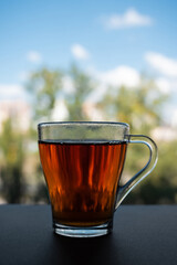 A glass cup of fragrant tea stands near the window