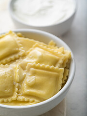Delicious Italian ravioli and sour cream sauce. Macro photography. White background. Pastel shades. Food design, restaurant, hotel, cafe, cookbook, culinary blog.