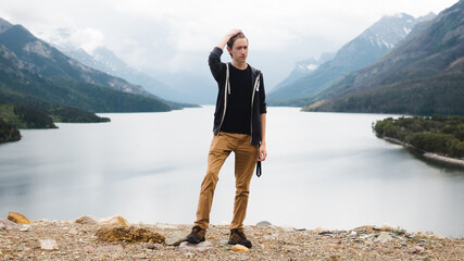 Fototapeta na wymiar man posing in front of a beautiful lake and mountains