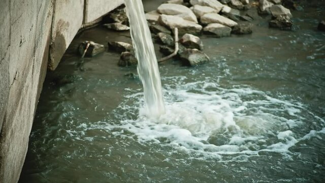 Discharge of dirty water from a drain into a small river or pond Stock video. Drain pipe or sewer release wastewater into river. Sewage or domestic wastewater or municipal wastewater.