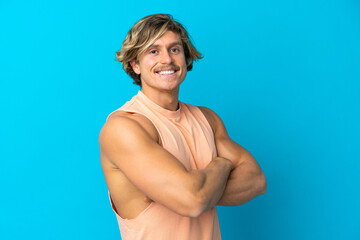 Handsome blonde man isolated on blue background with arms crossed and happy