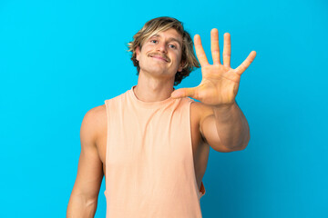 Naklejka premium Handsome blonde man isolated on blue background counting five with fingers