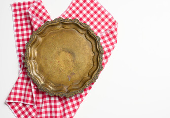 red cotton napkin and empty copper round vintage plate on white background, fruit dish. View from...