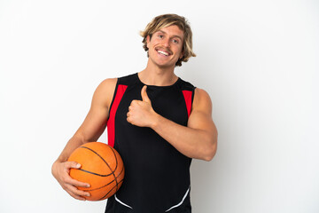 Young blonde man holding a ball of basketball isolated on white background giving a thumbs up gesture