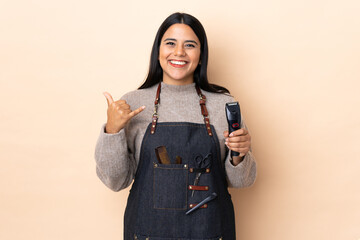 Young Colombian woman hairdresser isolated on beige background making phone gesture
