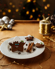 Sweet Christmas Gingerbread Star Cookies decorated with royal icing on a white plate, wood table,  Christmas Celebration mood, Christmas lights in the background