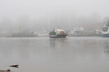 Fototapeta premium the boat sails into the river port in fog