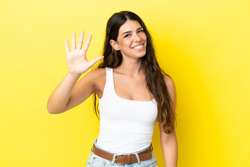 Young caucasian woman isolated on yellow background counting five with fingers