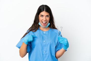 Dentist woman holding tools over isolated white background with surprise facial expression