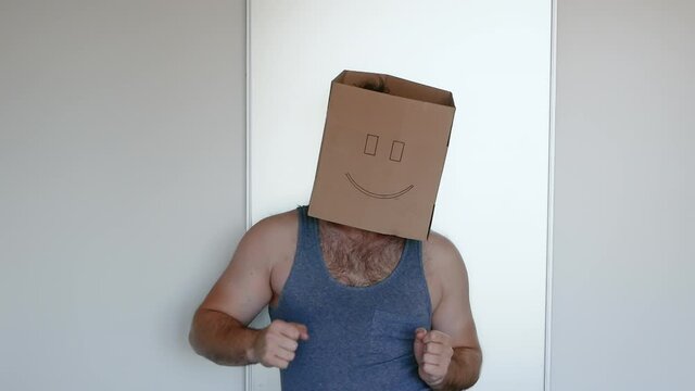 A man with a box on his head is dancing, there are noises in the video. Freak with a smile.
