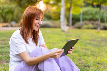 Obraz premium Young pretty redhead woman at outdoors holding a tablet