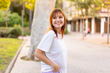 Young pretty redhead woman at outdoors with happy expression