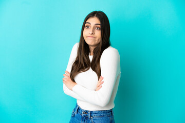 Young caucasian woman isolated on blue background making doubts gesture while lifting the shoulders