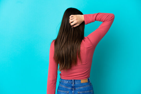 Young caucasian woman isolated on blue background in back position and thinking