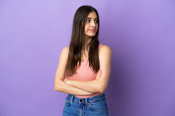 Young caucasian woman isolated on purple background keeping the arms crossed
