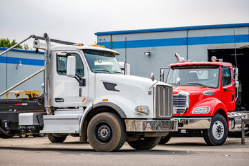 Fototapeta na wymiar Two skid-mounted big rigs day cab semi trucks for transporting waste containers are parked in a warehouse awaiting another order