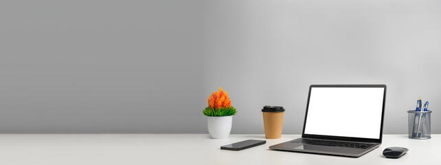 isolated, Blank white screen laptop on a white table in office. Working concept using technology smartphones, notebook, internet. Copy space on left for design, Closeup, Gray, and blurred background