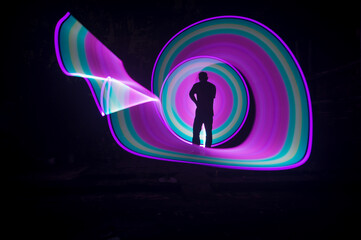 	
One person standing alone against a Colourful circle light painting as the backdrop	
