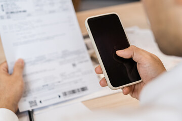 Cost, budget asian young man calculate expense, spending and check from invoice, use smartphone, mobile phone pay payment internet online of credit card at home. Technology of finance, financial.