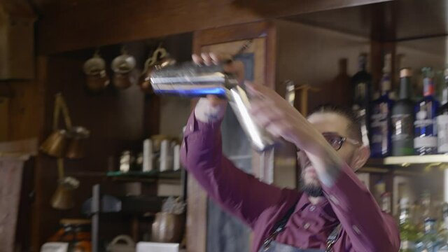 A bartender prepares his drink by mixing the ingredients