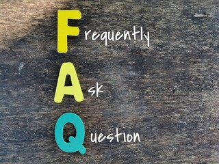 Word FAQ made of colourful wooden alphabet against wooden background.
