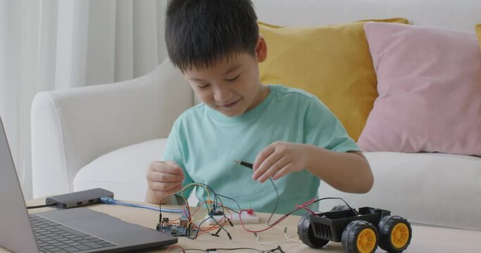 Asia people home school young small kid happy smile laugh self study online lesson excited make AI circuit toy. STEM STEAM digital class on laptop for active children play arduino enjoy fun hobby.