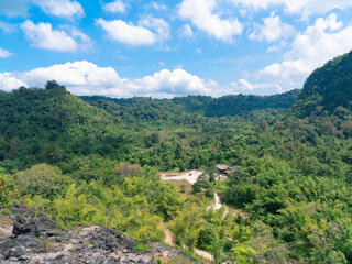 Fototapeta na wymiar fresh green forest and road view with bright cloudy blue sky from above old mining rock mountain in Thong Pha Phum, Kanchanaburi, Thailand 