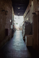 An old alley with goods on the sides covered with cloth and a bamboo ceiling with light bulbs in Souq Waqif in Qatar