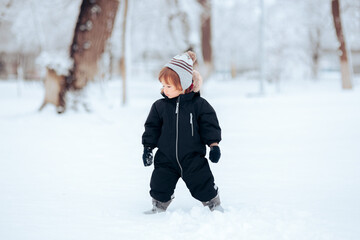 Fototapeta na wymiar Adorable Baby Girl Standing in Snow Wearing Warm Clothes