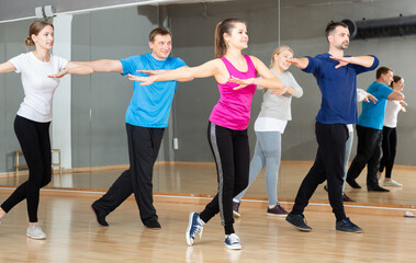 Fototapeta na wymiar Cheerful people practicing vigorous lindy hop movements in dance class..