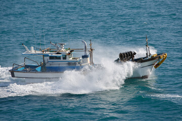 The fishing boat in sea splashes, floats with high speed.