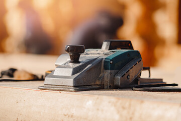 Industrial work carpenter grinds log with electric jointer, construction frame building site of house made of wood