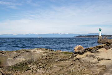 A ferry and mountains in the distance and rocky coast in the foreground