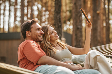 Woman with man taking selfie on tablet