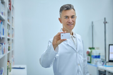 Confident man at pharmacy checkout showing card