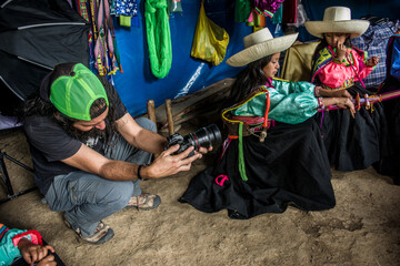 Fotógrafo  realiza fotografías a dos niñas latinoamericanas andinas que tejen con el telar de cintura