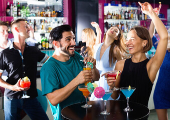 Glad smiling man with woman are drinking cocktails on corporate party.